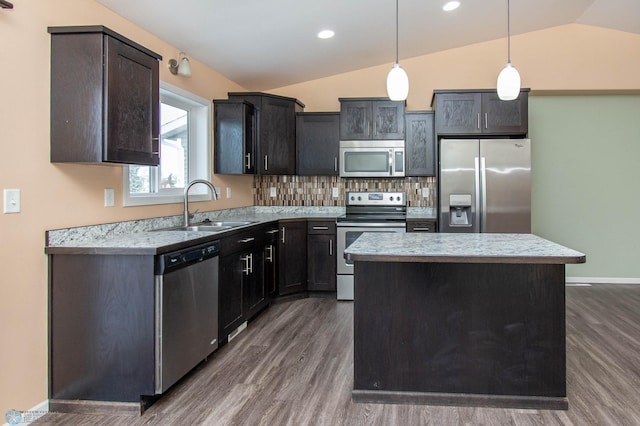 kitchen featuring lofted ceiling, stainless steel appliances, a sink, a center island, and decorative light fixtures