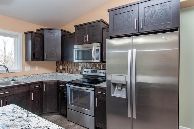 kitchen featuring lofted ceiling, appliances with stainless steel finishes, a sink, and dark brown cabinetry