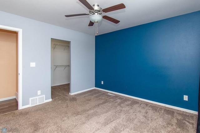 unfurnished bedroom with a closet, visible vents, a spacious closet, carpet flooring, and baseboards