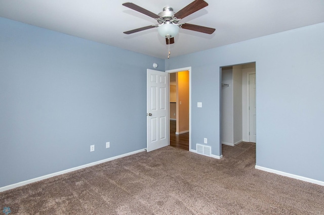 unfurnished bedroom featuring ceiling fan, dark colored carpet, visible vents, and baseboards