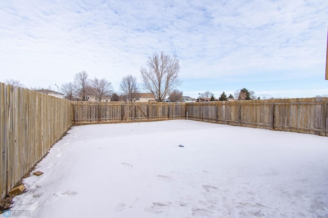 yard layered in snow featuring a fenced backyard