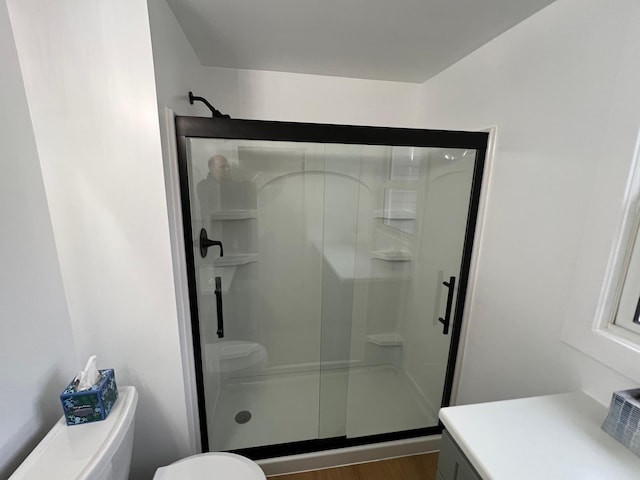 bathroom with vanity, a shower with door, toilet, and hardwood / wood-style floors