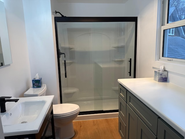 bathroom with hardwood / wood-style floors, sink, an enclosed shower, and toilet