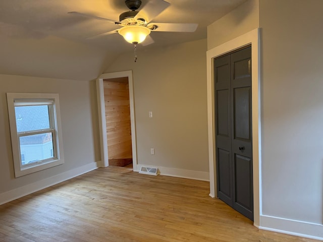 unfurnished bedroom featuring light wood-type flooring, a closet, ceiling fan, and lofted ceiling