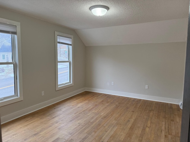 bonus room with a textured ceiling, lofted ceiling, and light hardwood / wood-style flooring