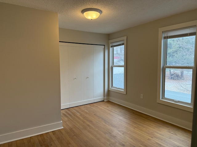 unfurnished bedroom with light hardwood / wood-style floors, a closet, and a textured ceiling