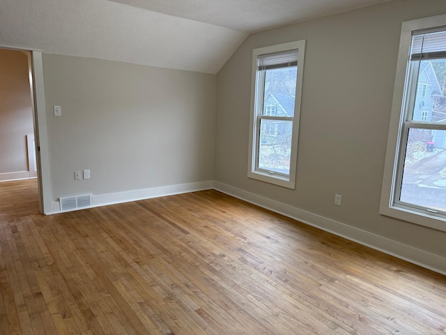 bonus room with light hardwood / wood-style flooring, a textured ceiling, and lofted ceiling