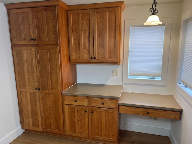 kitchen featuring light hardwood / wood-style floors, pendant lighting, and built in desk