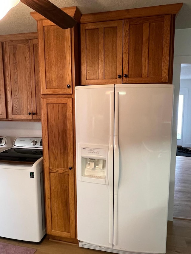 kitchen with white refrigerator with ice dispenser, wood-type flooring, separate washer and dryer, and a textured ceiling