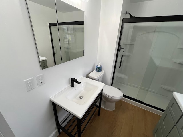 bathroom featuring hardwood / wood-style flooring, sink, a shower with door, and toilet