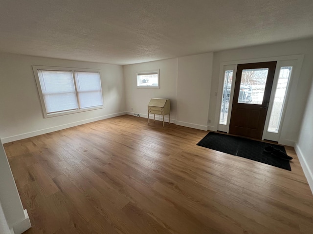 foyer entrance with light wood-type flooring and a textured ceiling