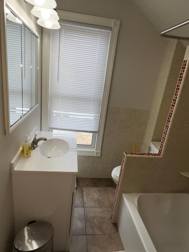 bathroom featuring tile walls, toilet, vanity, and tile patterned floors