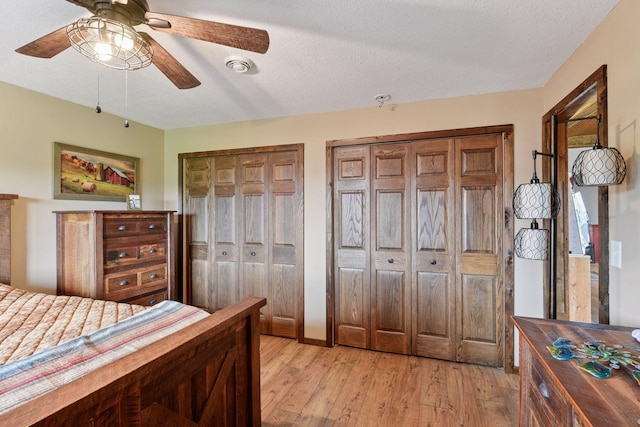 3685 Watertown Rd, Orono, MN 55359 - bedroom featuring two closets, light wood-type flooring, a textured ceiling, and a ceiling fan