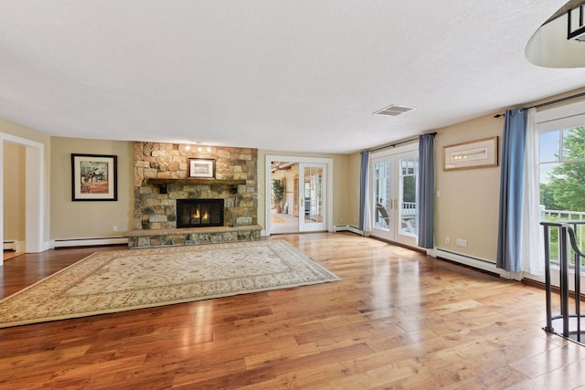 3685 Watertown Rd, Orono, MN 55359 - unfurnished living room with a baseboard heating unit, wood finished floors, a fireplace, baseboards, and a textured ceiling