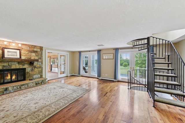 3685 Watertown Rd, Orono, MN 55359 - unfurnished living room featuring a textured ceiling, french doors, hardwood / wood-style flooring, a fireplace, and baseboard heating