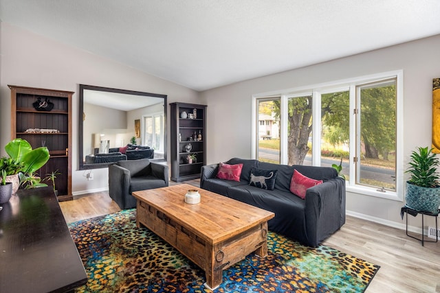 living room featuring lofted ceiling, a wealth of natural light, and light hardwood / wood-style flooring