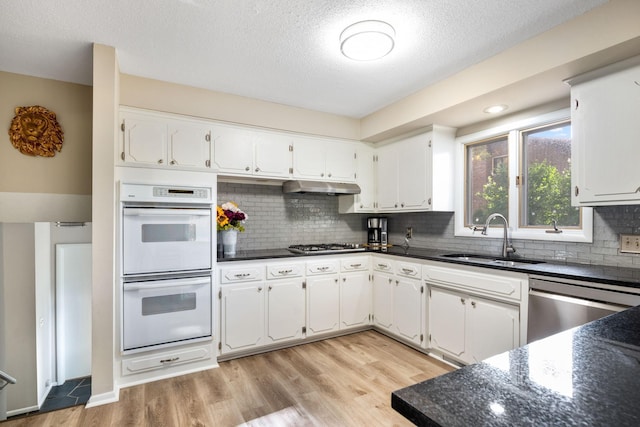 kitchen featuring sink, white cabinetry, light hardwood / wood-style flooring, appliances with stainless steel finishes, and decorative backsplash