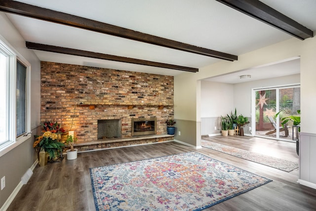 unfurnished living room featuring beamed ceiling, hardwood / wood-style floors, a wealth of natural light, and a fireplace