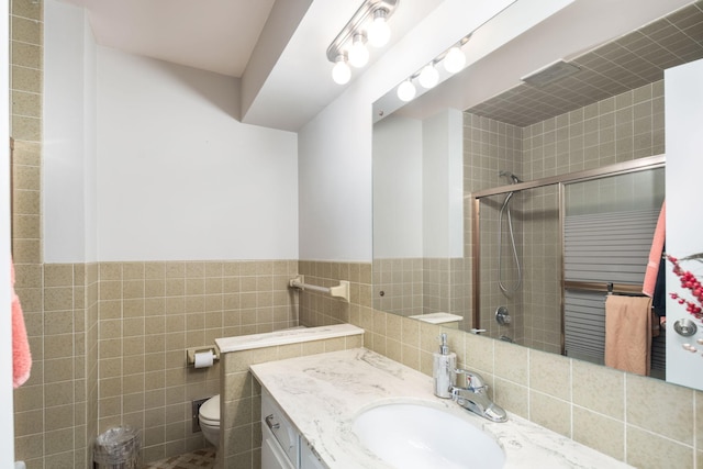 bathroom featuring vanity, a shower with shower door, tile walls, and toilet