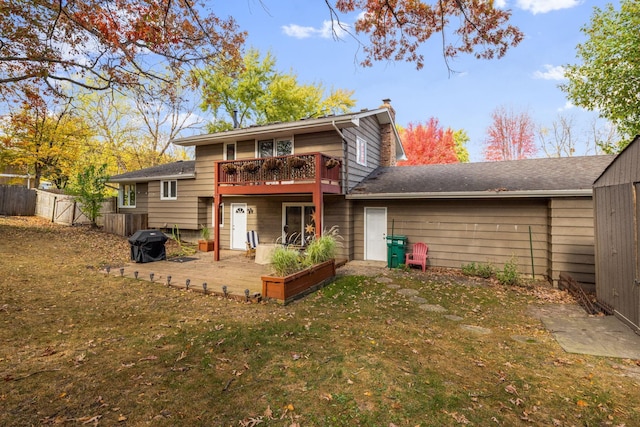 back of property featuring a wooden deck, a patio, and a lawn