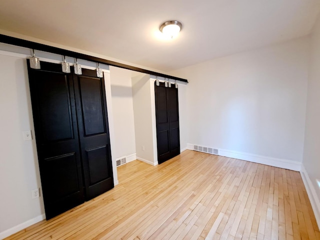 unfurnished bedroom featuring wood-type flooring and a barn door