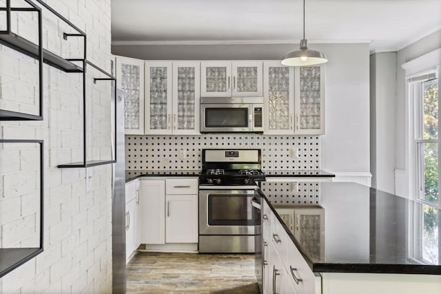 kitchen with stainless steel appliances, white cabinetry, hardwood / wood-style flooring, and decorative light fixtures