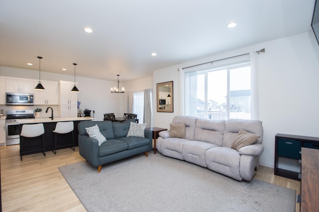 living room with an inviting chandelier and light hardwood / wood-style flooring