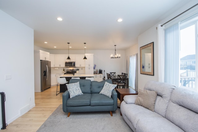 living room featuring an inviting chandelier, sink, and light hardwood / wood-style floors