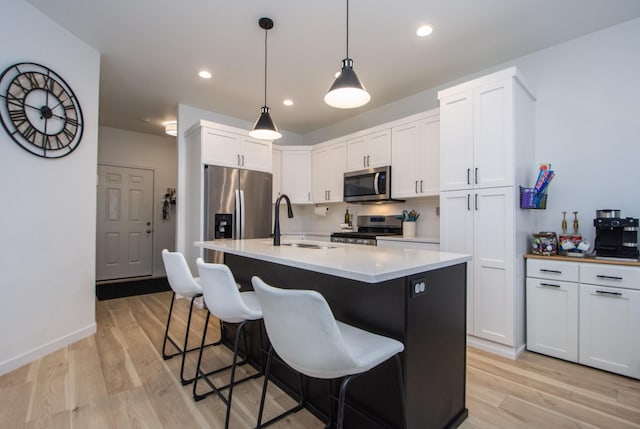 kitchen featuring sink, light wood-type flooring, appliances with stainless steel finishes, decorative backsplash, and white cabinets