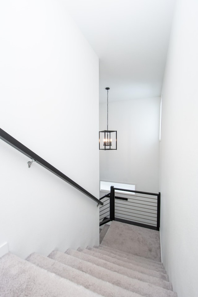 stairway with a chandelier and carpet floors