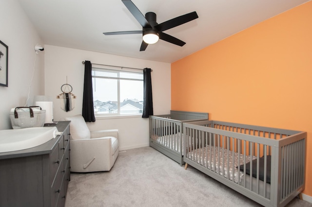 carpeted bedroom with a nursery area, sink, and ceiling fan