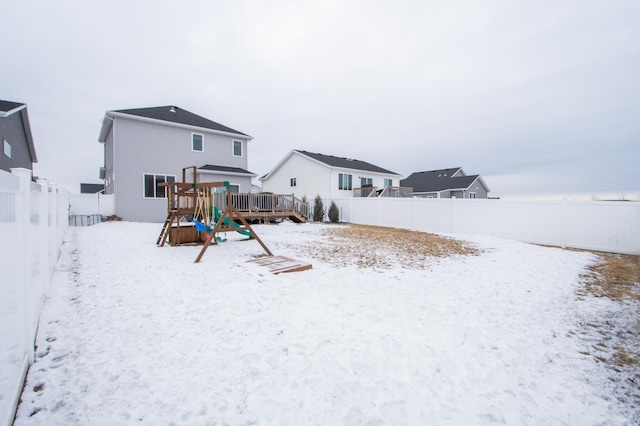 snow covered rear of property with a playground