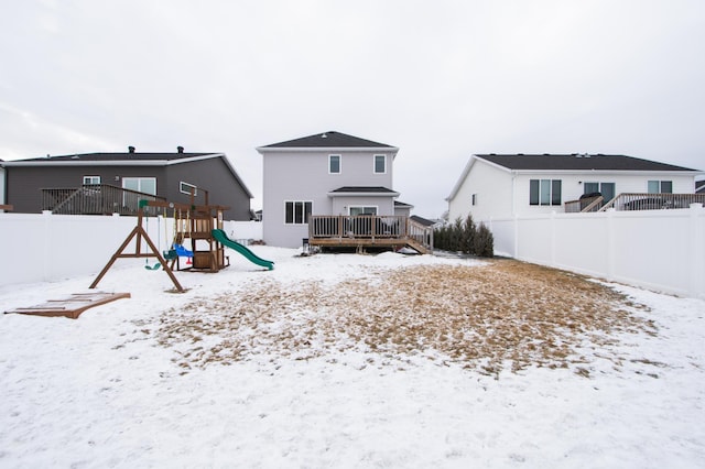 snow covered rear of property with a playground