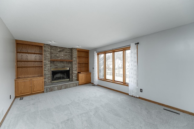 unfurnished living room featuring built in shelves, a fireplace, and light carpet