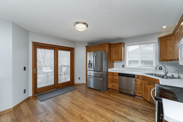 kitchen featuring stainless steel appliances, sink, and light hardwood / wood-style flooring