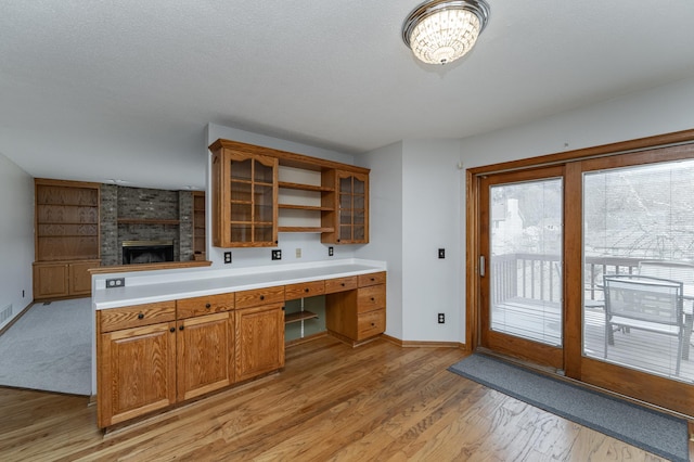 kitchen with a fireplace, built in desk, light hardwood / wood-style flooring, and a textured ceiling