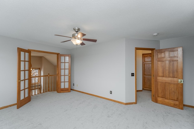 empty room featuring french doors, ceiling fan, light carpet, and a textured ceiling