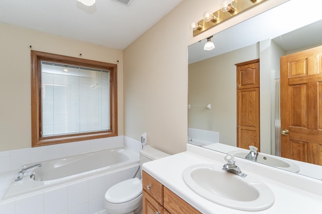 bathroom featuring tiled tub, vanity, and toilet