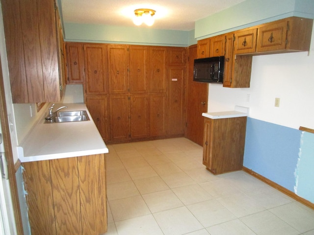 kitchen featuring black microwave, sink, and light tile patterned flooring