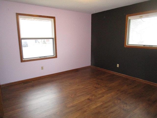 spare room with dark hardwood / wood-style flooring and a wealth of natural light