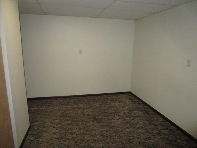 carpeted spare room featuring a drop ceiling