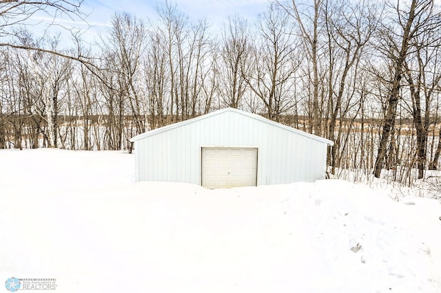 snow covered garage featuring an outbuilding