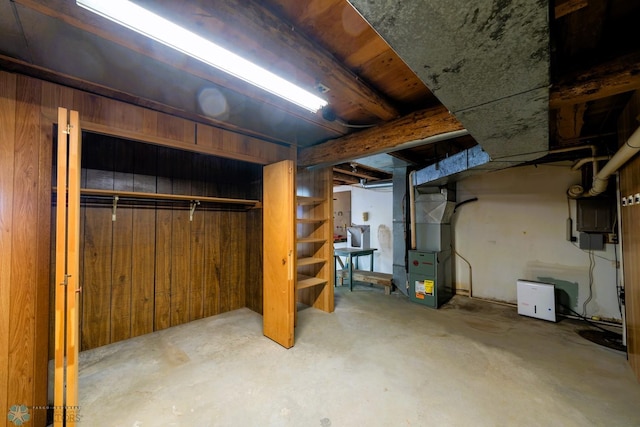 basement featuring wooden walls and heating unit