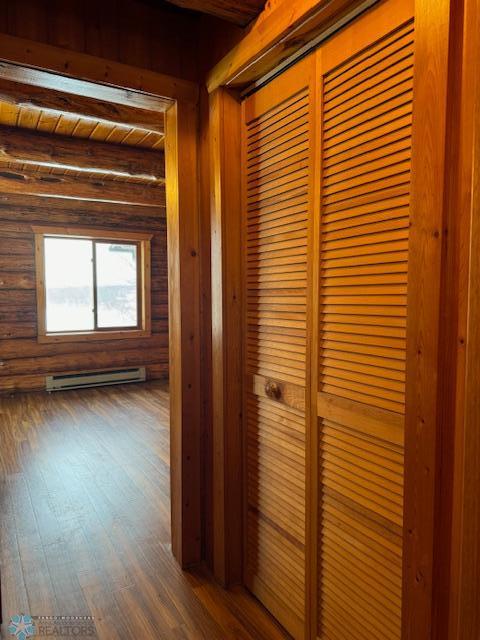 hallway featuring dark hardwood / wood-style flooring, a baseboard radiator, and beamed ceiling