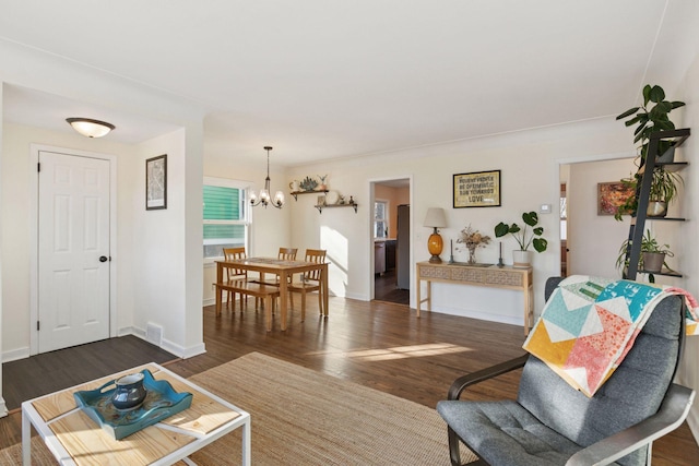 living area with dark wood-style floors, baseboards, visible vents, and an inviting chandelier