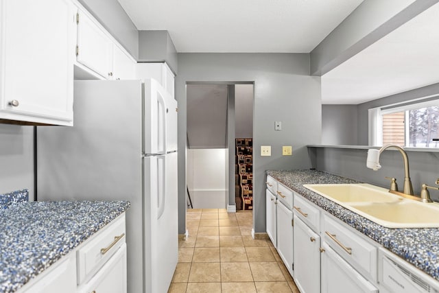 kitchen featuring white cabinetry, sink, dark stone countertops, white refrigerator, and light tile patterned floors