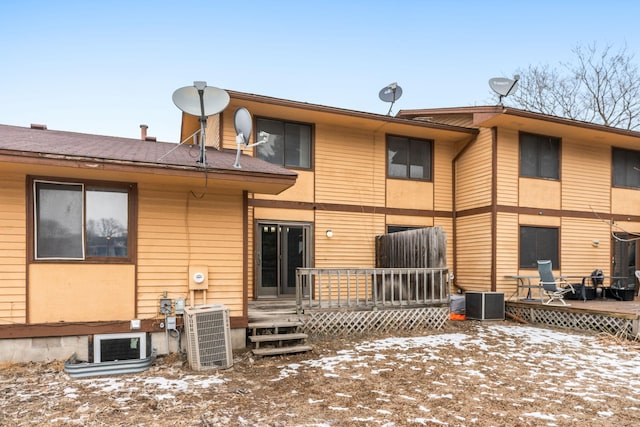 snow covered property with a wooden deck and central AC