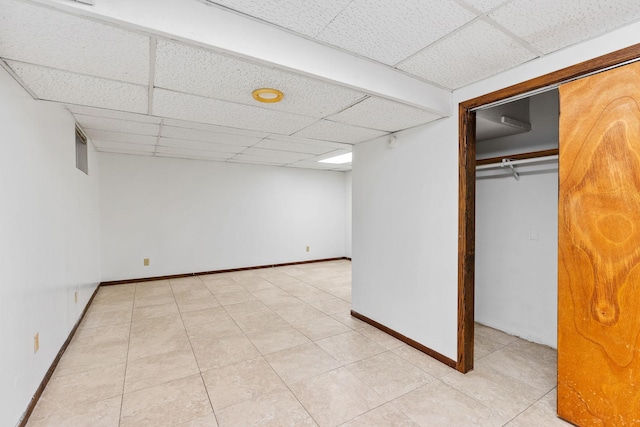 basement featuring a paneled ceiling and light tile patterned flooring