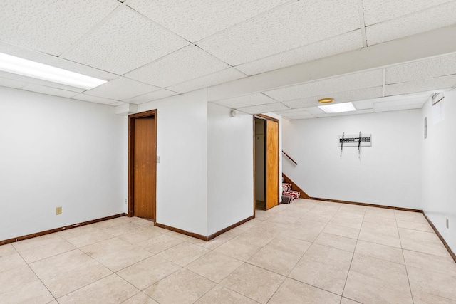 basement featuring a drop ceiling and light tile patterned flooring