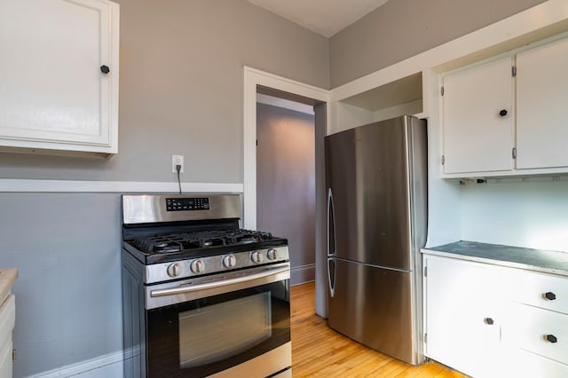 kitchen featuring stainless steel appliances, light countertops, white cabinets, and light wood-style floors